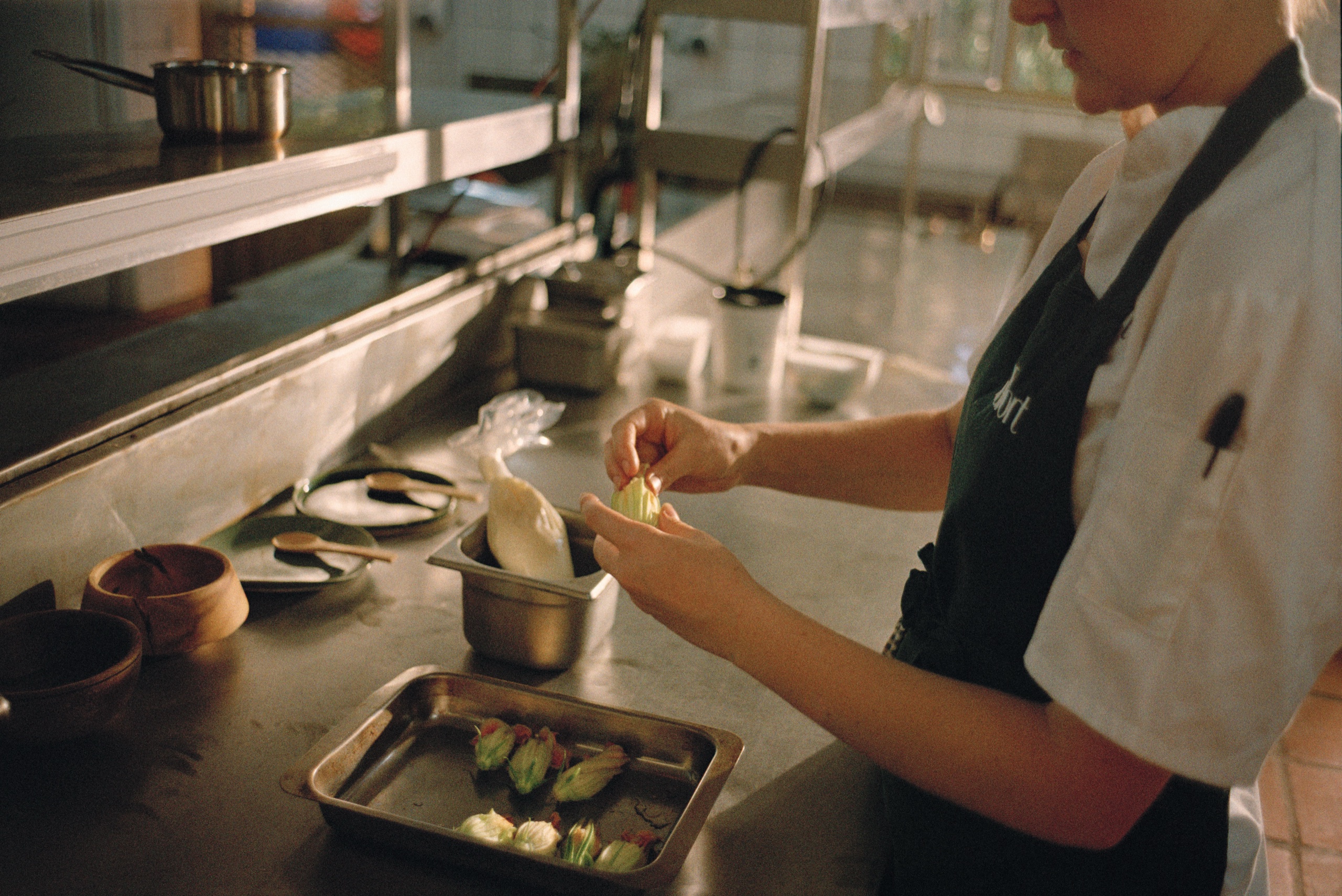 A chef prepares zucchini flowers at the kitchen pass